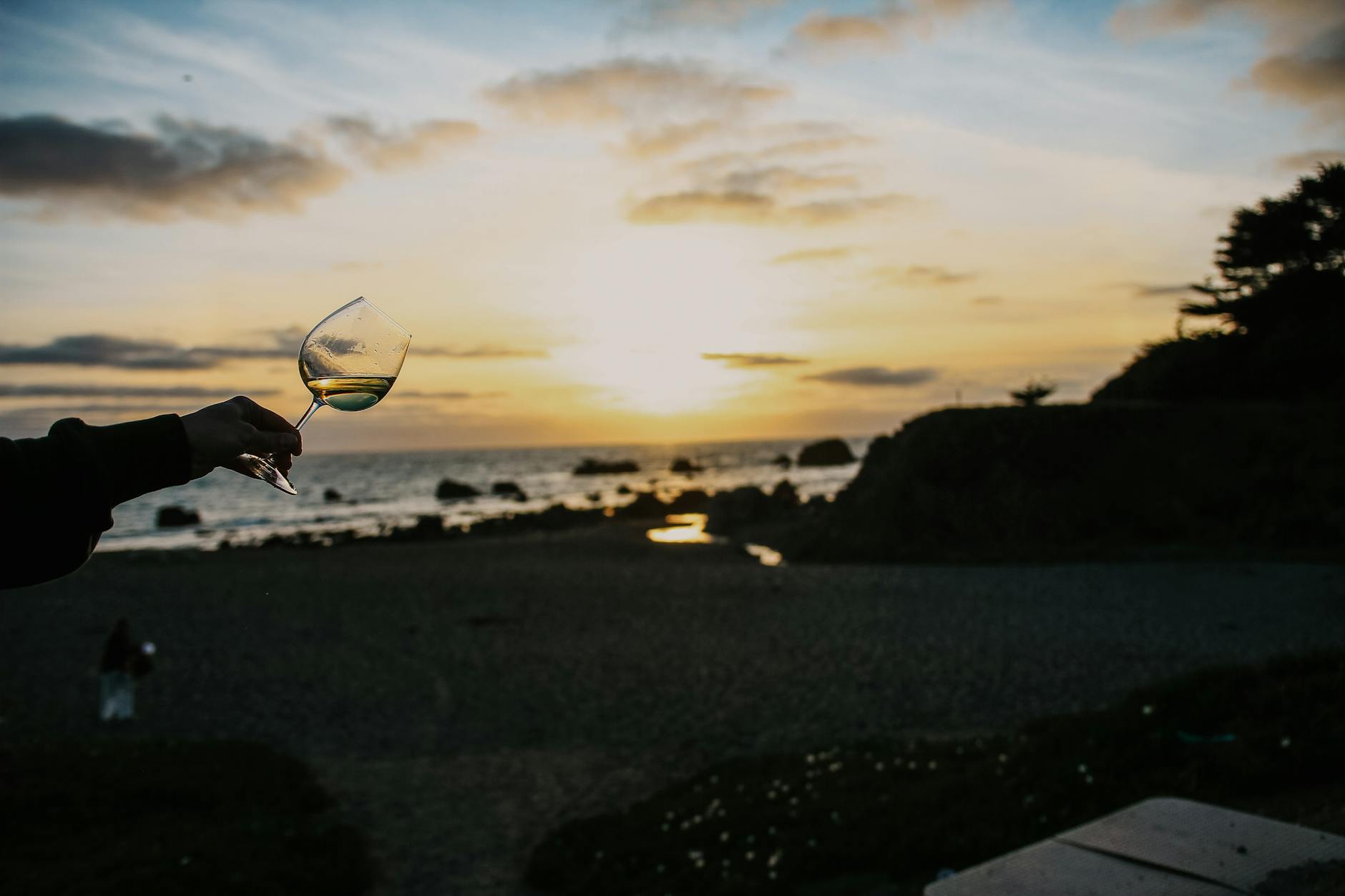 A glass of Cloudy Bay Sauvignon Blanc on a table with a blurred vineyard in the background.
