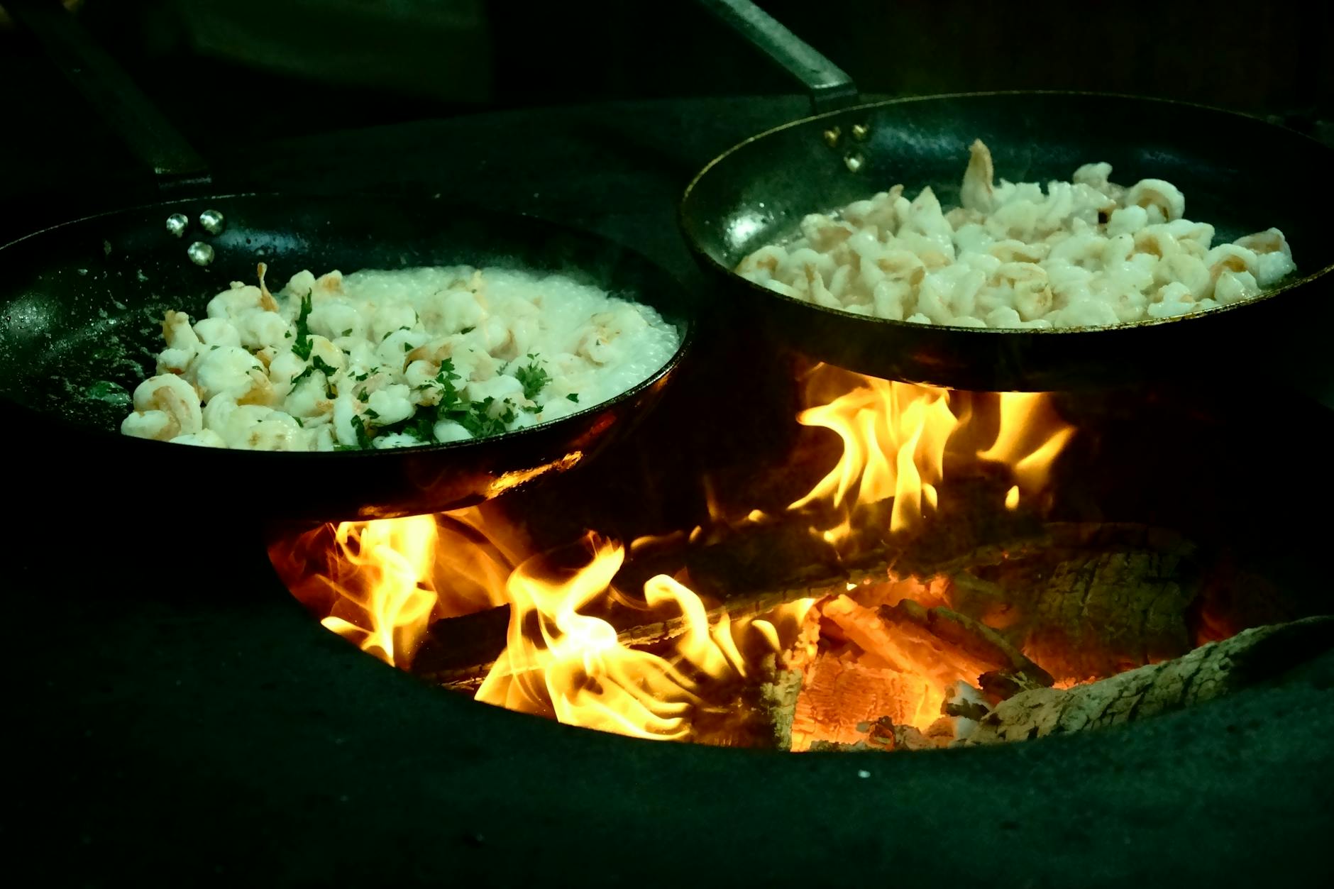 Chef's hand carefully flipping shrimp in a pan during cooking.